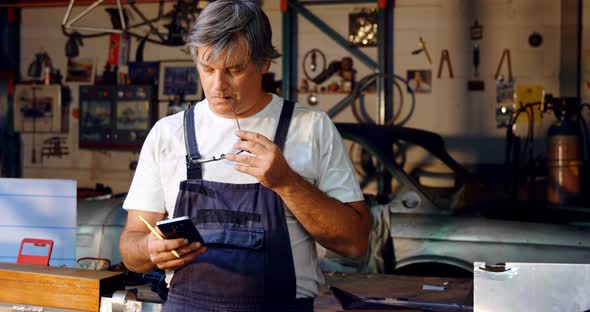 Male mechanic using mobile phone alt