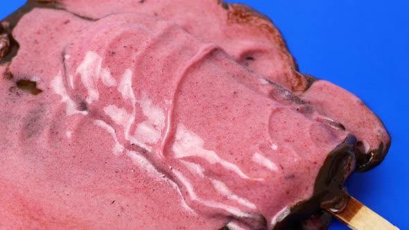 The chocolate ice cream sundae lies on a blue background and melts slowly. 4K video food close-up. alt