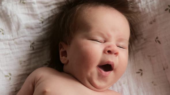Cinematic video portrait newborn baby yawns, sleepy cute baby child. alt