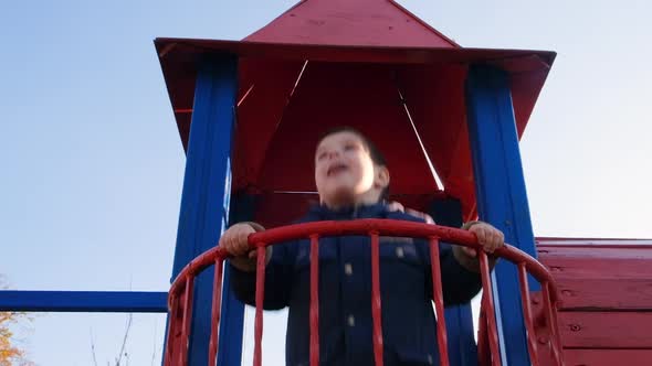 A Child Jumps on the Balcony of the Castle on the Playground Against the Sky alt