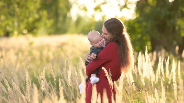 Happy young mum and baby playing together outdoor enjoy beautiful field of sunshine alt