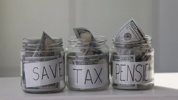 Female hand puts 100 dollars in a glass jar with the text save . Concept of saving money.