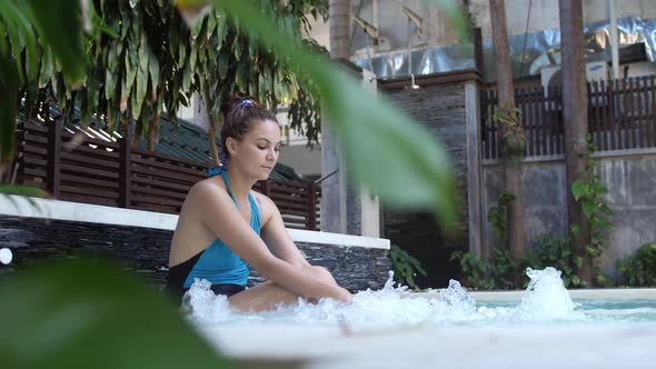 Beautiful Young Woman Relaxes in a Hydromassage Jacuzzi in Swimming Pool