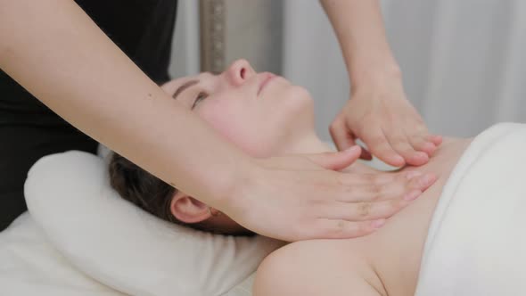 Female therapist massages clavicle and chest of young woman. Relaxing massage. Therapeutic massage.