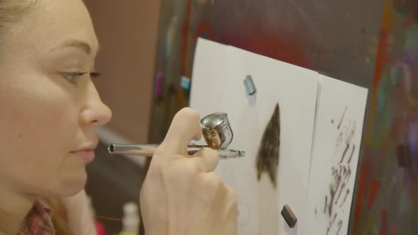 Woman Artist Learns to Paint with Airbrush with Acrylic Dye Paper and Easel