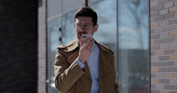 Stylish Man Making Voice Message or Using Virtual Assistant App on Mobile Phone alt