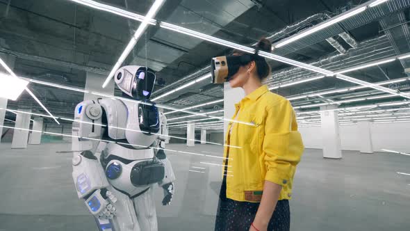 Human-like Robot Is Touching a Hand of a Woman in VR-glasses alt