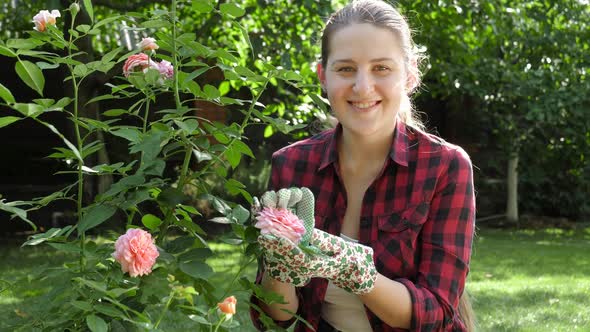 Happy Smiling Woman Posing in Her Garden with Blooming Roses alt