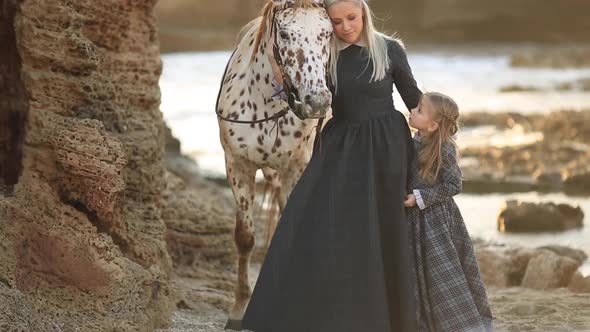 Mom and Daughter Stroking a White Horse