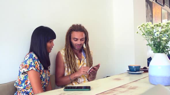 Attractive black hair asian girl with caucasian dreadlock man sitting at the table in coffee shop an alt