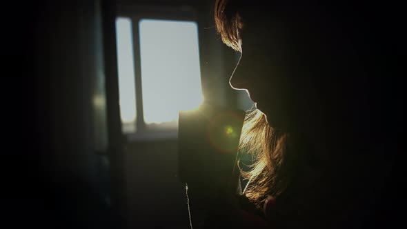 Silhouette of a Pretty Brunette Woman Drinking Coffee in the Sunset Sun Glare