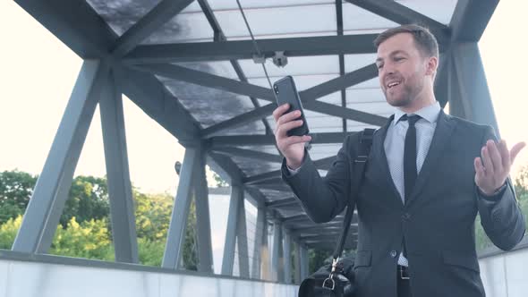 Successful Businessman Holds a Smartphone He Communicates Via Video Link alt