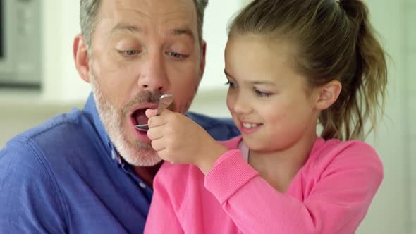 Daughter feeding her father with spoon alt