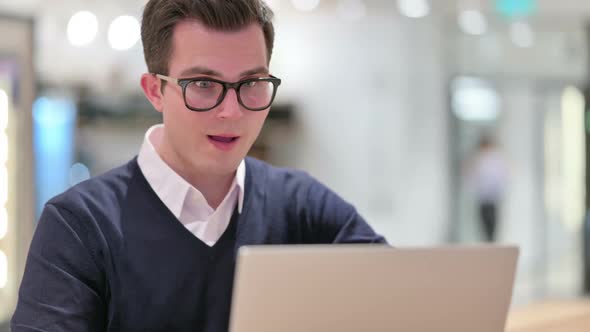Young Businessman Celebrating Success on Laptop alt
