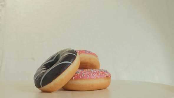 Three Donuts on a Smooth Surface Rotate Against a Gray Background