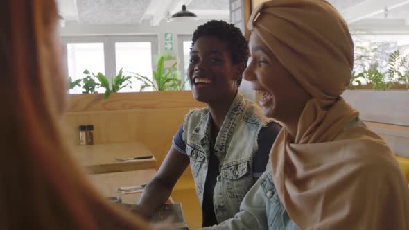 Young adult female friends hanging out in a cafe alt