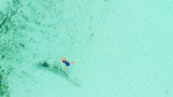 Aerial slow motion: top down woman swimming on turquoise transparent water alt