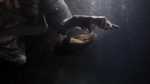 Sexy Fashion Model Is Tumbling Underwater Slow Motion Shot in Darkness and Depth of Swimming Pool alt