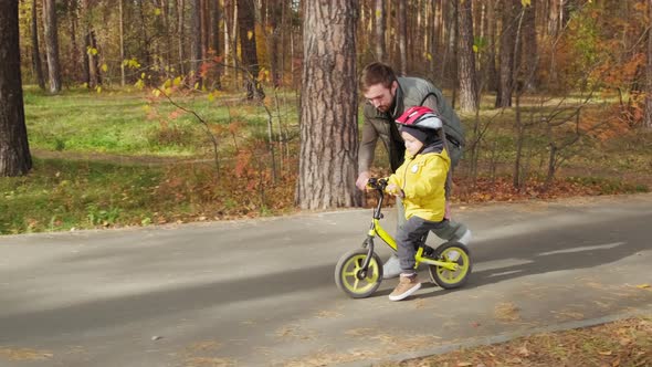 Father Teaching Son To Ride Balance Bicycle alt