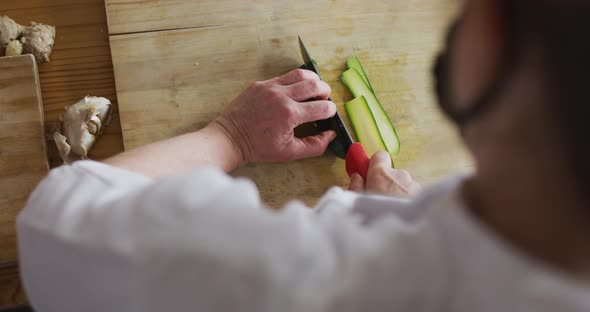 Caucasian female chef cutting zucchini alt