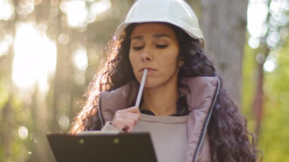 Female Technician with Clipboard Taking Measures for Reforestation of Woodlands alt