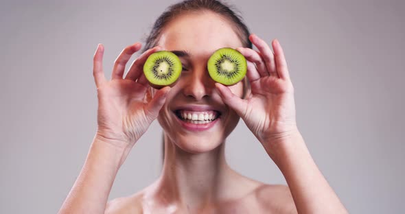 Girl Hiding Her Eyes with Kiwi Slices alt