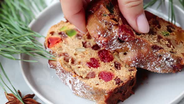 Piece of Christmas fruit cake on a plate in festive decorations alt