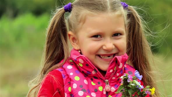 A portrait of a cute little girl. Beautiful Little girl enjoys the smell of flowers in the meadow