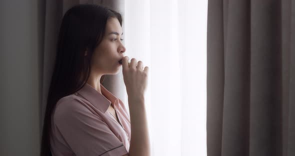 Young Woman is Standing Near the Window in the Room and Vaping alt