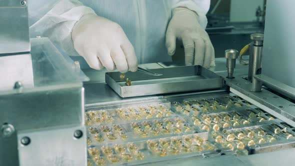 Pharmacologist Checks Tubes with Liquid Moving on a Conveyor. Pharmacy Industry, Medical Factory alt