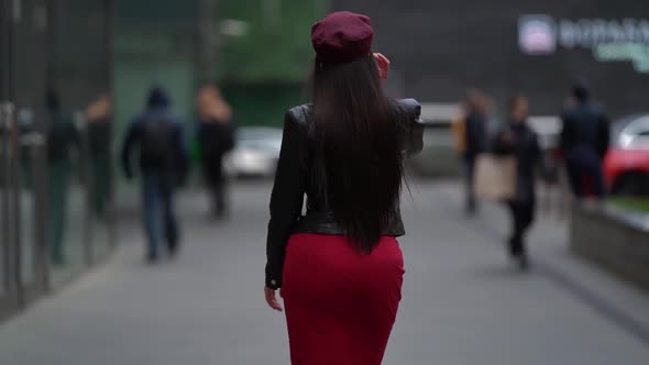 a Brunette with Long Hair in a Black Leather Jacket a Red Skirt and a Burgundy Cap Walks Away alt