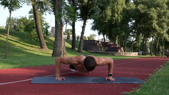 Strong Man with Muscular Fit Body Doing Pushups with Clapping on Fitness Mat Pumping Muscles alt