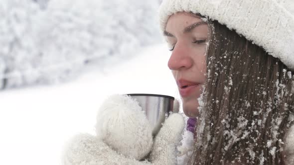 Portrait of a Beautiful Young Woman Who Drinks Some Hot Drink After a Snowball Fight alt