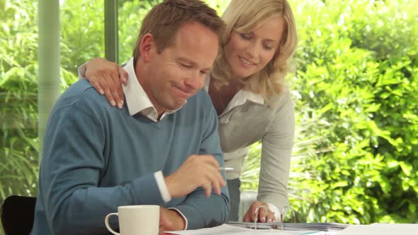 Mid Shot of male and female at dinning table looking at personal finance alt