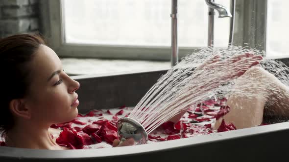 Girl Lies in a Stone Bath with Foam and Petals Washes Herself alt