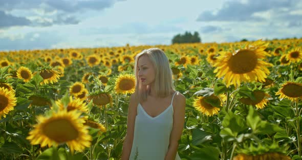 Beautiful Girl Walks in a Field with Sunflowers, She Is Happy. Romantic Walk in the Field in Summer alt