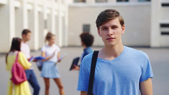 Young Man Student Looking at Camera Against College Building alt