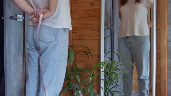 Middle Section of Slender 30s Aged Female Measuring Her Waist with Length Tape and Looking at Own alt
