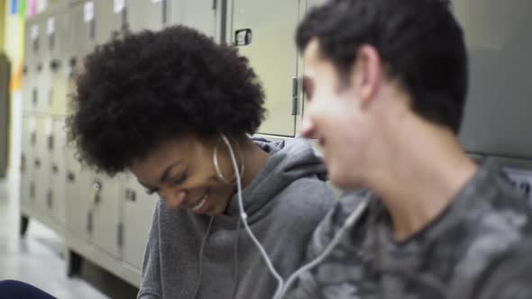 Teenage boy and girl sharing earphones and listening to music