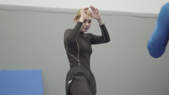 Portrait of Female Blond Trainer Teaching Unrecognizable Athletic Man How To Do Elbow Punch in Muai alt