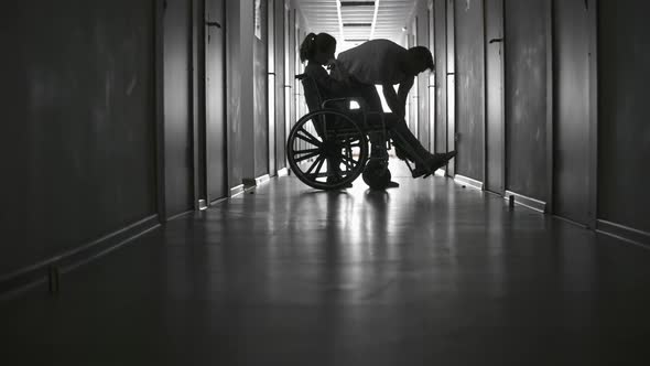 Unrecognizable Man Pushing Wheelchair of Ill Woman alt