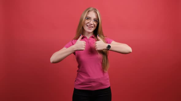 Portrait of Attractive Young Woman Showing a Thumbs Up on Red Background alt