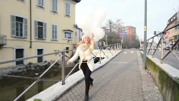 Slow motion young beautiful blonde woman running holding balloons alt