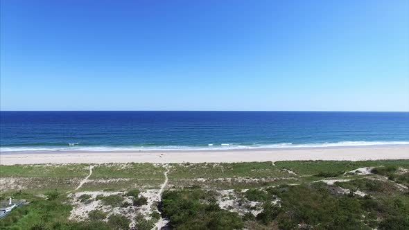 Aerial shot of beach with water in the foreground alt