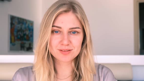 Young Alluring Blonde Woman with Blue Eyes Looks Peacefully Into the Camera  Slow Motion alt