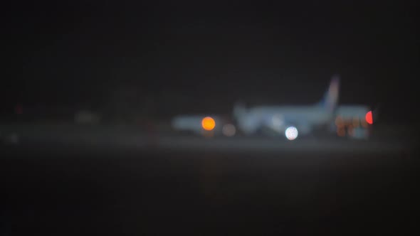 Night view of plane and aircraft tow tractor at the airport, defocus alt