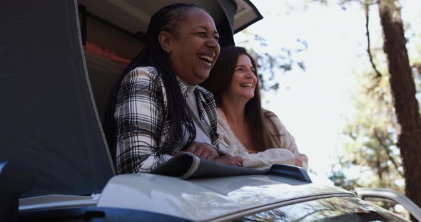 Senior women friends having fun traveling around the mountains with camper van alt