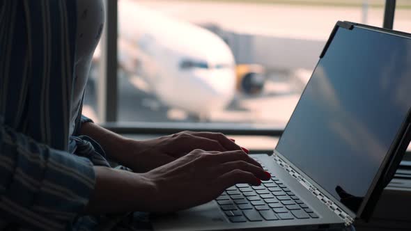 Close-up, Female Hands Are Typing on a Laptop Against Panoramic Window Background. with Passenger alt