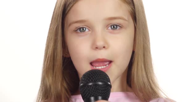 Child Girl Sings the Song Into the Microphone. White Background. Close Up alt
