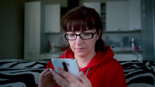 Woman with Glasses at Home Uses Phone Chat with Friends Read Some Information Cinematic Shot
